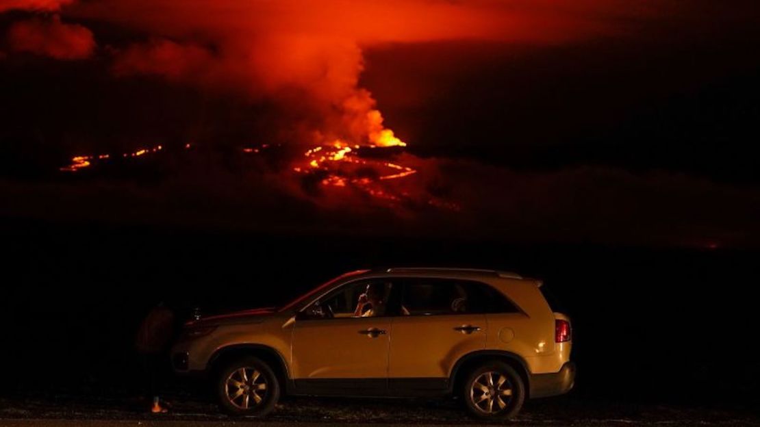 Un hombre habla por teléfono en su automóvil junto a la Saddle Road mientras el volcán Mauna Loa entra en erupción, el 30 de noviembre cerca de Hilo, Hawai.