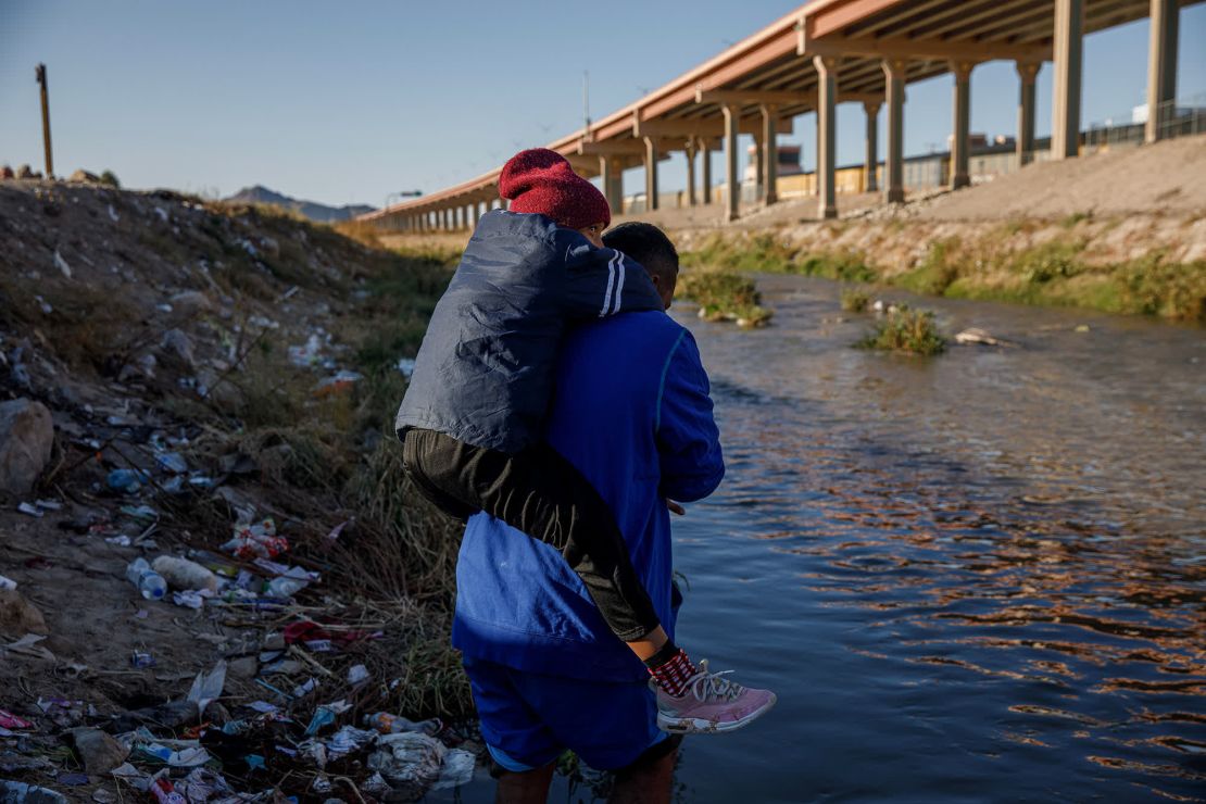 Un hombre carga a un niño antes de cruzar el Río Grande, que divide la ciudad mexicana de Ciudad Juárez y El Paso, Texas.