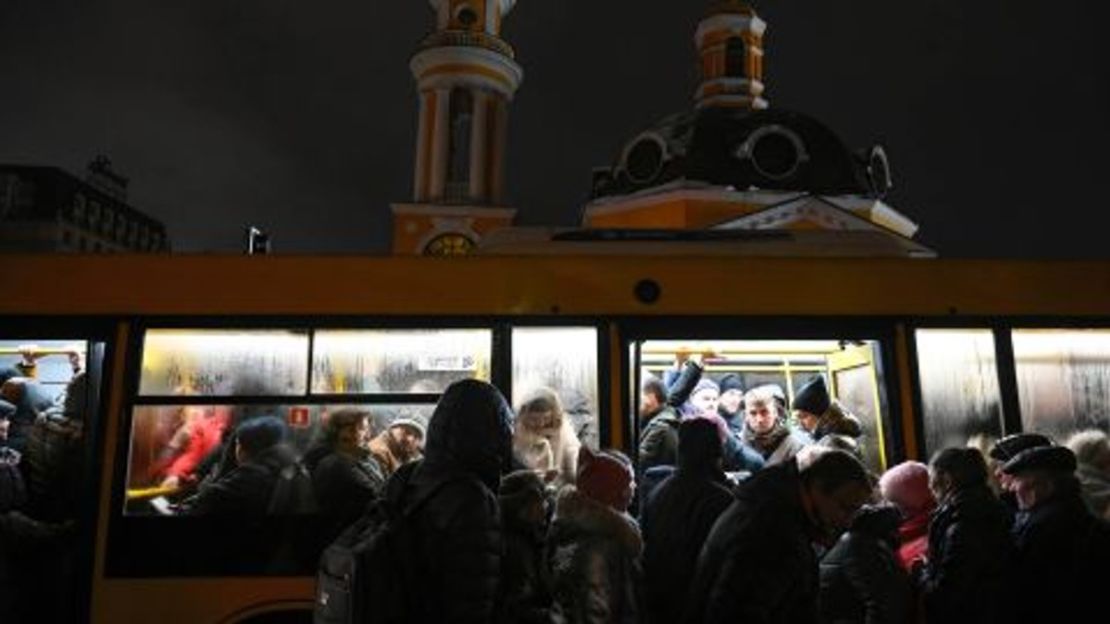 La gente se sube a un autobús lleno de personas en una parada de transporte público en Kyiv durante un apagón.