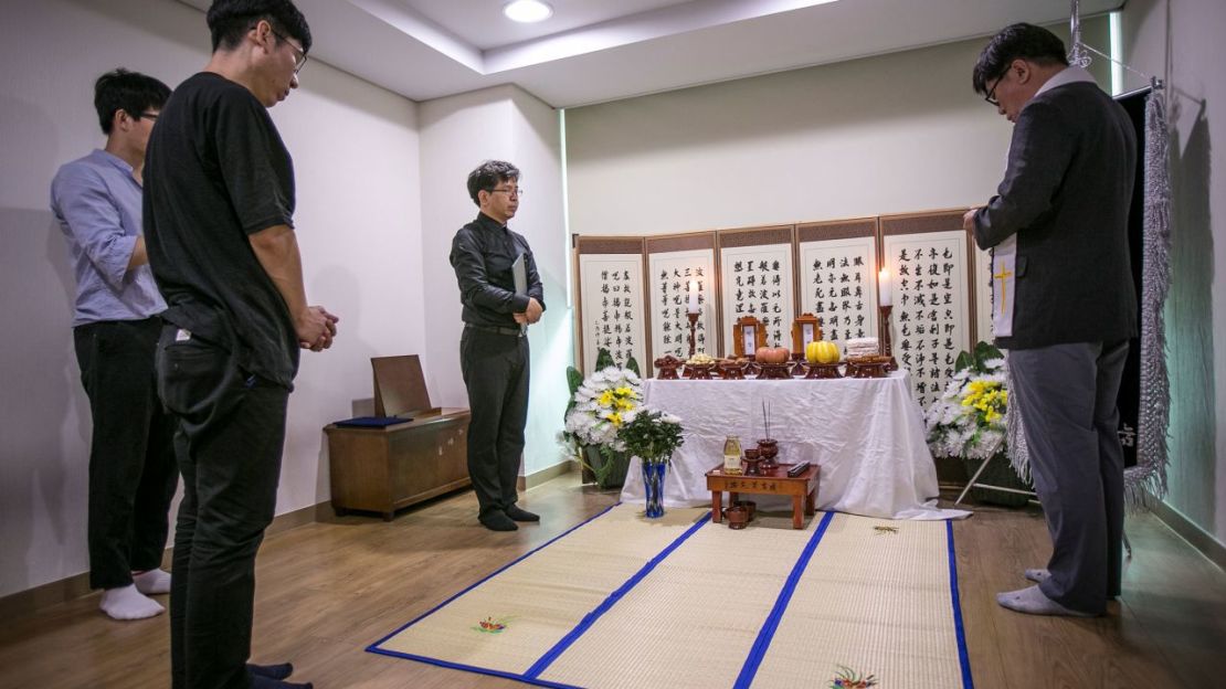 Un pastor voluntario reza ante un santuario improvisado para dos personas que murieron en "muertes solitarias", dentro de la sala de espera de un crematorio el 4 de julio de 2016 en Goyang, Corea del Sur. Crédito: Jean Chung/Getty Images