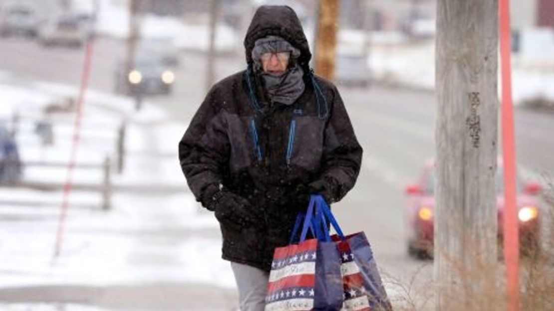 Greg Behrens, de Des Moines, Iowa, intenta mantenerse caliente mientras avanza por una acera cubierta de nieve, el miércoles 21 de diciembre de 2022, en Des Moines, Iowa.