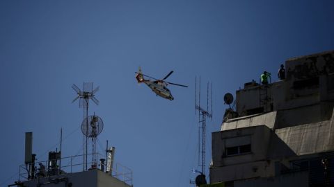 A helicopter flies over fans waiting for the bus with Argentina's players to through an avenue to celebrate after winning the Qatar 2022 World Cup tournament in Buenos Aires on December 20, 2022. - Millions of ecstatic fans are expected to cheer on their heroes as Argentina's World Cup winners led by captain Lionel Messi began their open-top bus parade of the capital Buenos Aires on Tuesday following their sensational victory over . (Photo by Emiliano Lasalvia / AFP)
