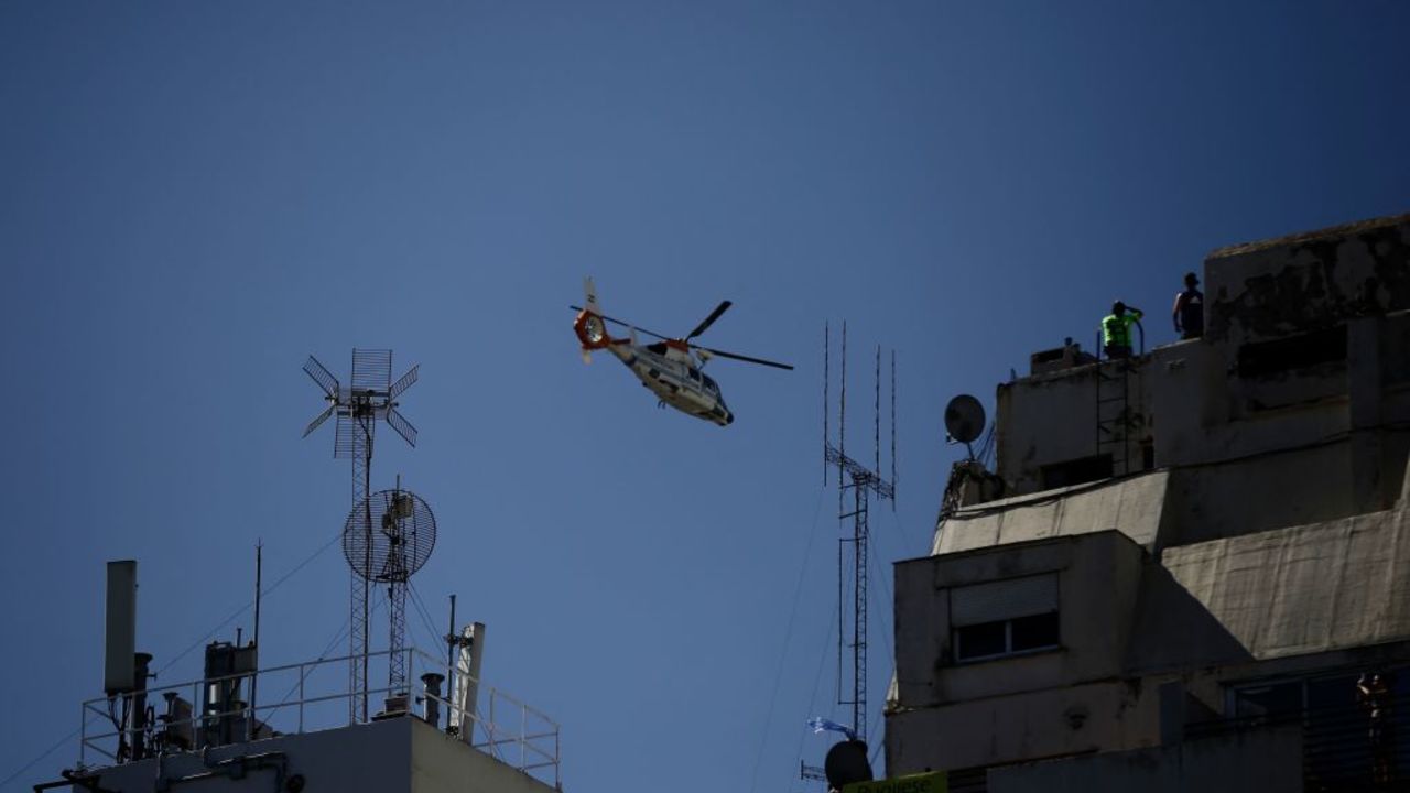 A helicopter flies over fans waiting for the bus with Argentina's players to pass through an avenue to celebrate after winning the Qatar 2022 World Cup tournament in Buenos Aires on December 20, 2022. - Millions of ecstatic fans are expected to cheer on their heroes as Argentina's World Cup winners led by captain Lionel Messi began their open-top bus parade of the capital Buenos Aires on Tuesday following their sensational victory over France. (Photo by Emiliano Lasalvia / AFP)