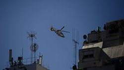 A helicopter flies over fans waiting for the bus with Argentina's players to pass through an avenue to celebrate after winning the Qatar 2022 World Cup tournament in Buenos Aires on December 20, 2022. - Millions of ecstatic fans are expected to cheer on their heroes as Argentina's World Cup winners led by captain Lionel Messi began their open-top bus parade of the capital Buenos Aires on Tuesday following their sensational victory over France. (Photo by Emiliano Lasalvia / AFP)