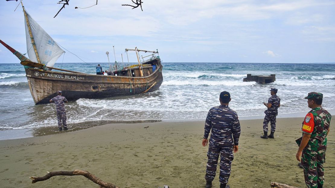 Personal militar indonesio inspecciona un bote de madera utilizado para transportar refugiados rohingya después de que aterrizó en la playa de Indra Patra en el pueblo de Ladong, provincia de Aceh, Indonesia, el domingo 25 de diciembre de 2022.