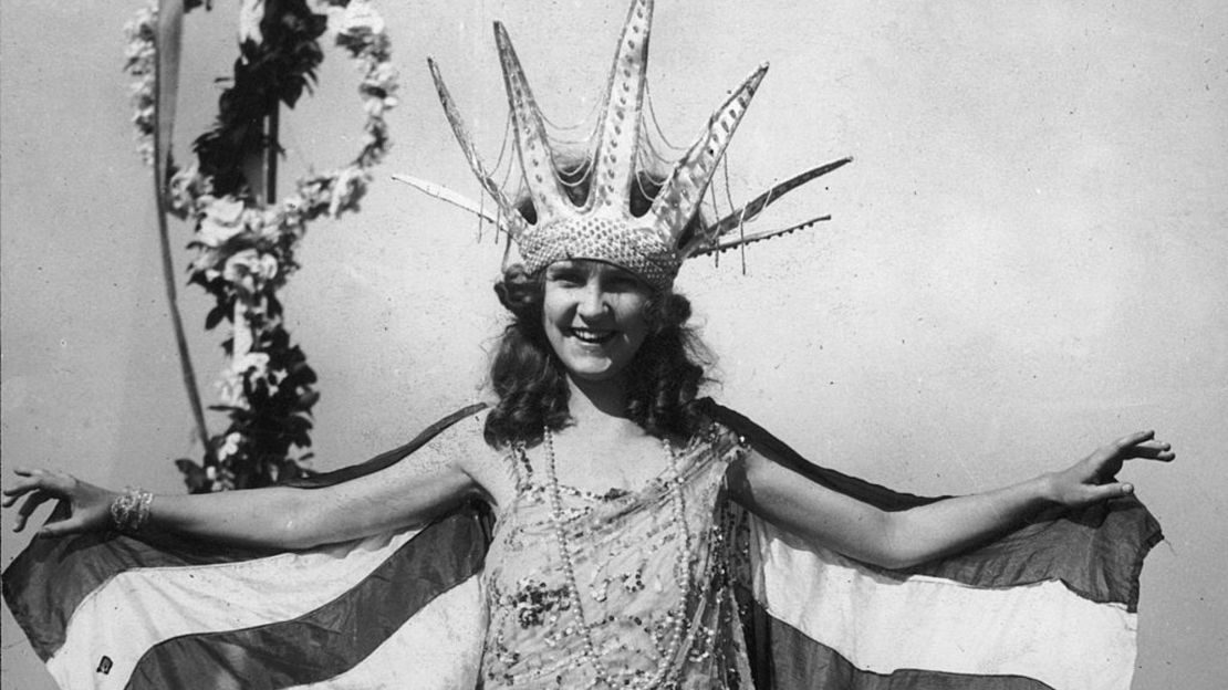 Margaret Gorman sonríe, con una gran corona de la Estatua de la Libertad y una capa a rayas, como la primera Miss América en Atlantic City, Nueva Jersey.