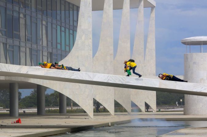 Simpatizantes de Bolsonaro se cubren el rostro mientras las fuerzas de seguridad lanzan gases lacrimógenos durante los enfrentamientos en el Palacio Presidencial de Planalto este domingo.