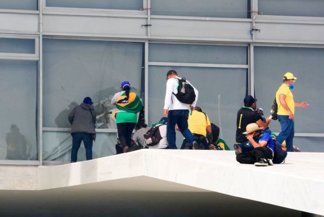 Simpatizantes de Bolsonaro rompen una ventana al invadir el Palacio Presidencial de Planalto este domingo.