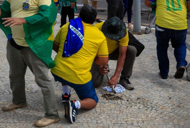 Simpatizantes de Bolsonaro dañan la acera para obtener piedras durante los enfrentamientos con la policía antidisturbios frente al Palacio Presidencial de Planalto.