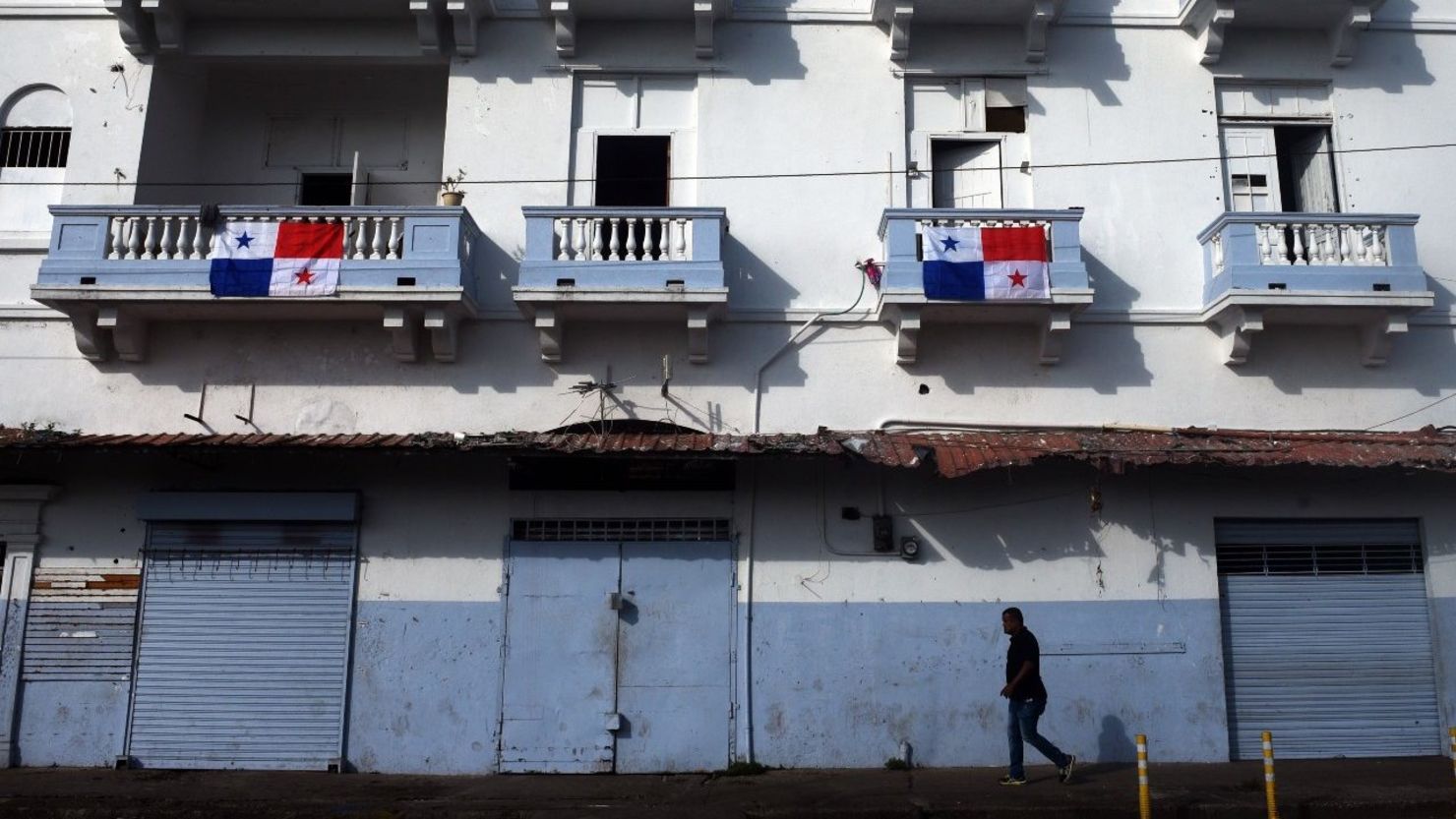 Un hombre camina frente a un edificio decorado con banderas panameñas durante un desfile para conmemorar el 114 aniversario de la independencia de Panamá de Colombia, en la Ciudad de Panamá el 3 de noviembre de 2017.