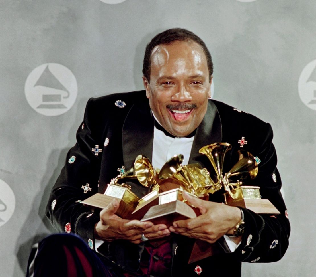 El estadounidense Quincy Jones saluda a los fotógrafos con las manos llenas con sus seis premios Grammy el 20 de febrero de 1991 en el Radio City Music Hall. Jones acumula hasta la fecha un total de 28 premios Grammy