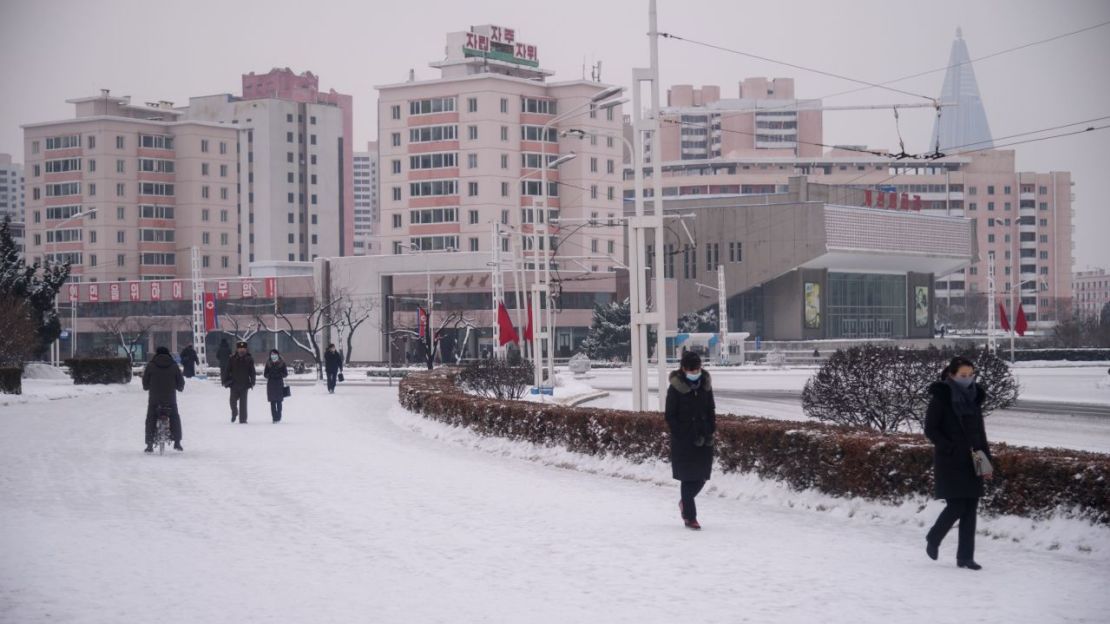 Personas caminan por una calle cubierta de nieve cerca del Arco del Triunfo en Pyongyang el 12 de enero de 2021.