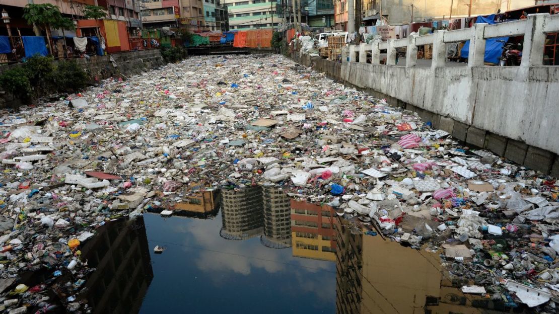 Edificio reflejado en las aguas de un río lleno de basura en Manila, el 23 de enero de 2016. Crédito: NOEL CELIS/AFP/AFP/Getty Images