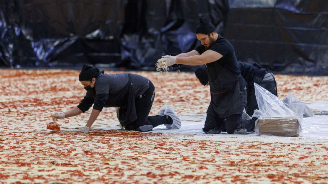 Cocineros trabajan dentro del Centro de Convenciones de Los Ángeles el 18 de enero de 2023 para crear la pizza más grande del mundo.