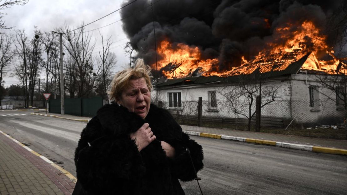 Una mujer frente a una casa en llamas en la ciudad ucraniana de Irpin el 4 de marzo de 2022, días después de que Rusia lanzara su invasión.