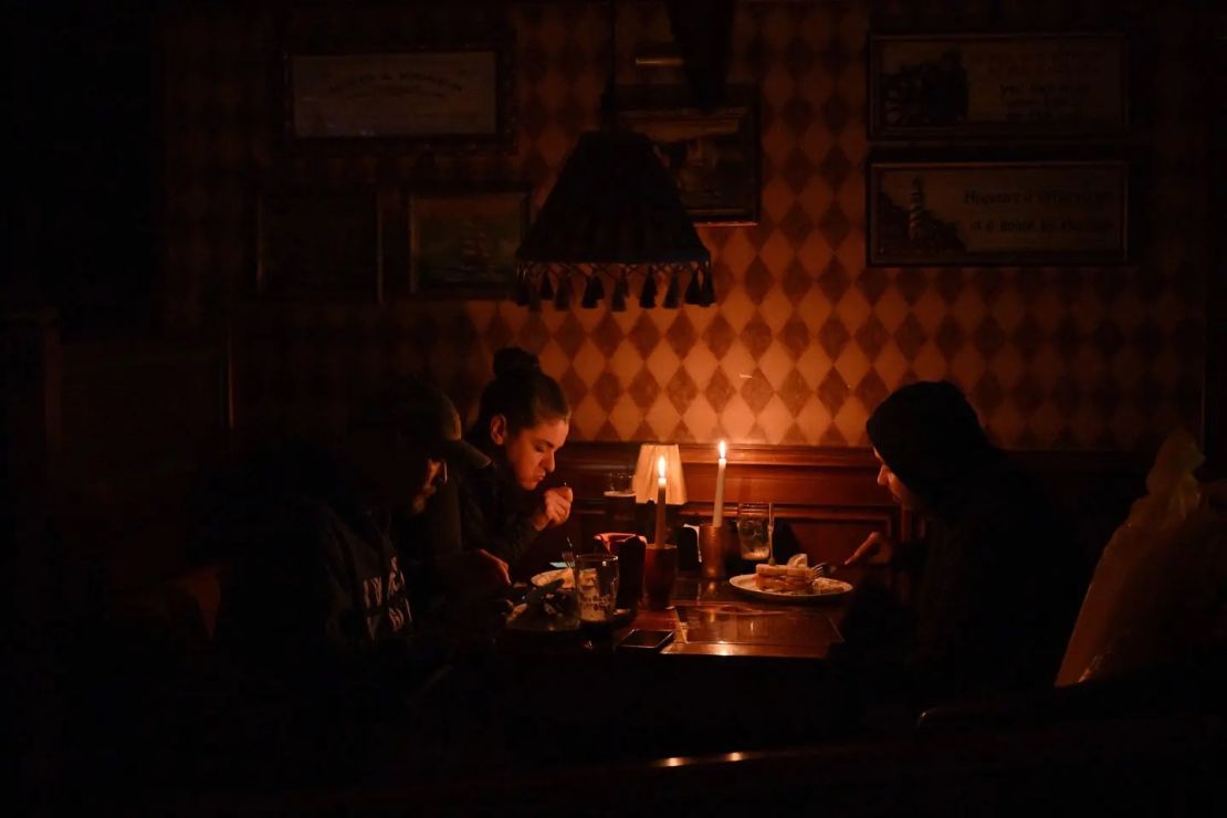 Personas comen a la luz de las velas durante un corte de energía en Kyiv.