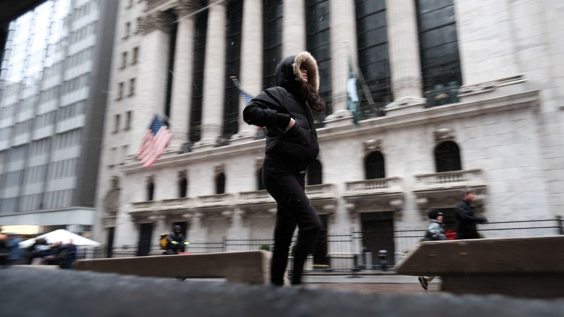 Personas caminan por el bajo Manhattan junto a la Bolsa de Nueva York (NYSE) bajo una ligera nevada el 14 de marzo de 2023 en la ciudad de Nueva York. Gran parte del noreste está siendo azotada por una tormenta invernal tardía que trae viento, lluvia y nieve a muchas zonas.