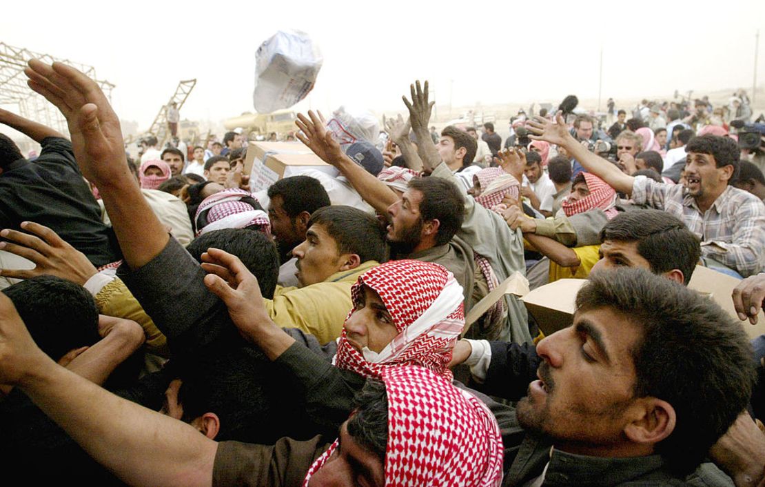 Cientos de iraquíes se reúnen en la parte trasera de un camión de la Media Luna Roja mientras se distribuye ayuda humanitaria, en forma de alimentos y agua, el 26 de marzo de 2003 en Safwan, Iraq.