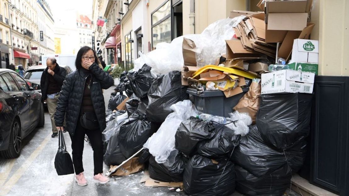 Una mujer se tapa la nariz mientras pasa junto a desechos apestosos en una calle del distrito 9 de París, pues los recolectores de basura se unieron a las protestas contra las reformas de las pensiones el 17 de marzo de 2023.