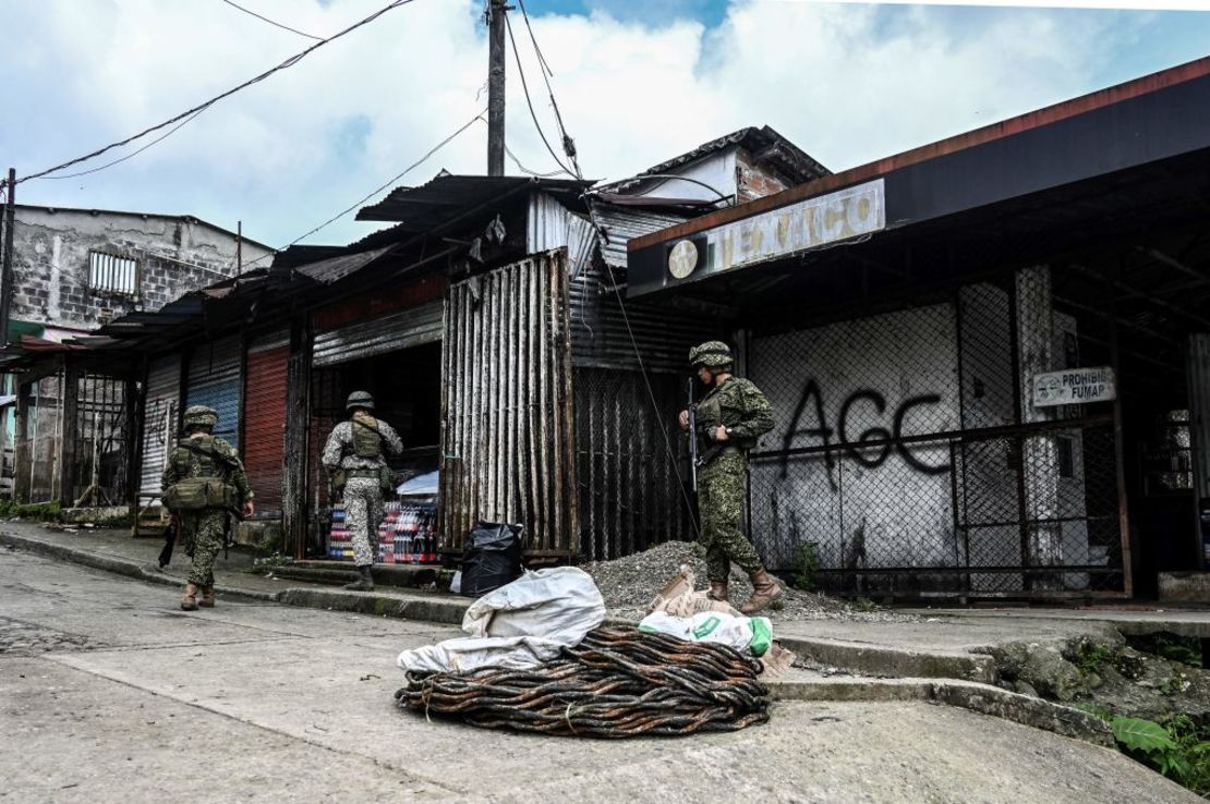 Soldaos colombianos hacen guardia junto a los grafitis de los paramilitares AGC Gaitanistas de Autodefensas de Colombia o Clan del Golfo cerca de Buenaventura, departamento del Valle del Cauca, el 18 de mayo de 2022. Crédito: JOAQUIN SARMIENTO/AFP via Getty Images