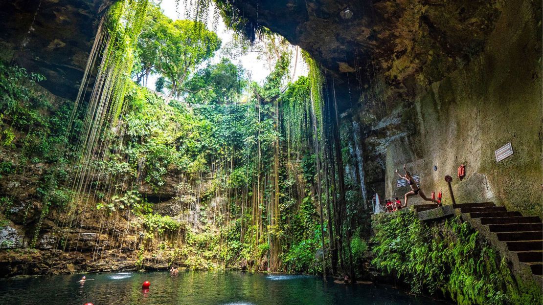 Turistas en el cenote Ik Kil a las afueras de Chichén Itzá, México. Los cenotes son enormes sumideros que se forman cuando el techo de una cueva se derrumba bajo el agua, creando una red de cavernas submarinas en aguas cristalinas. En la antigüedad, los cenotes constituían la única fuente de agua de la civilización maya, quienes creían que representaban un pasaje al inframundo, o “Xibalba” en lengua maya.