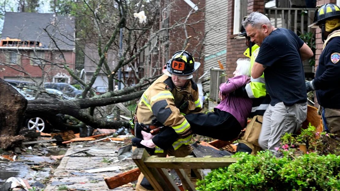 Los bomberos sacan a una mujer de su condominio después de que su complejo fuera dañado por un tornado el viernes en Little Rock, Arkansas.