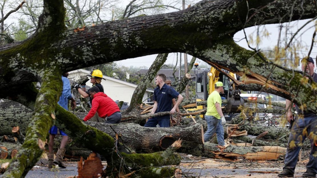 La policía y los bomberos reciben ayuda de voluntarios que limpian árboles caídos en Kiehl Avenue después de que las tormentas azotaran el área el viernes en Sherwood, Arkansas. Thomas Metthe/Arkansas Democrat-Gazette/AP