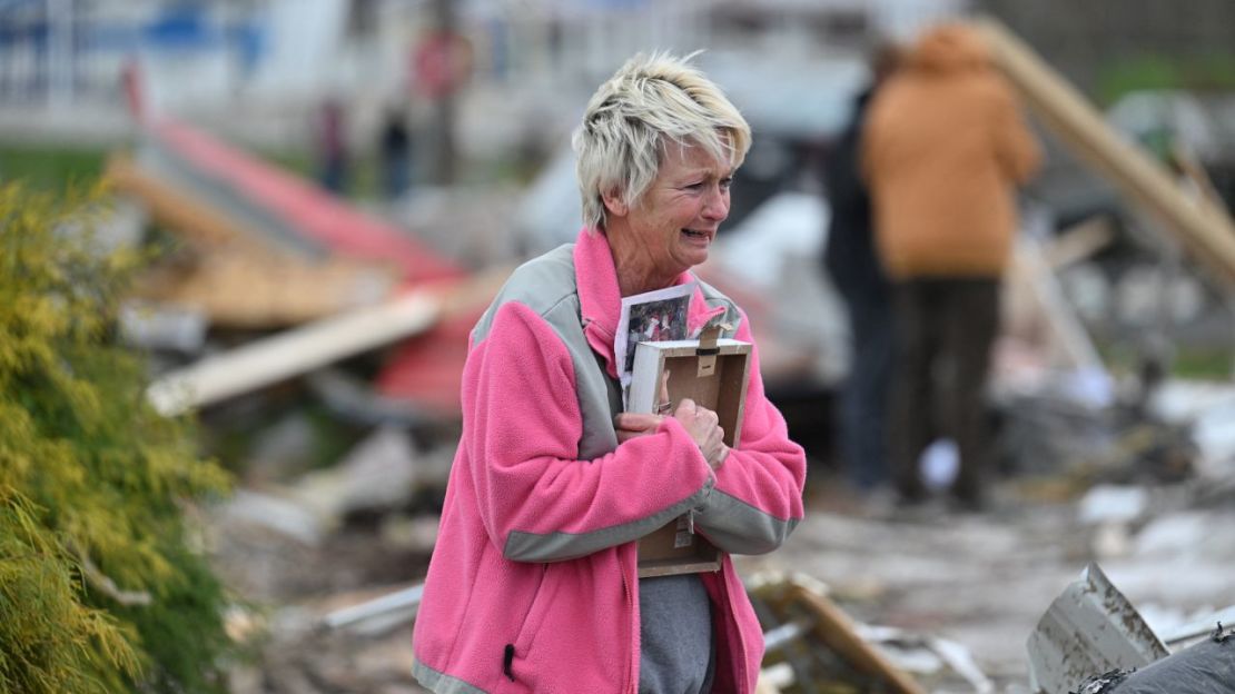 Debbie Lowdermilk sostiene fotografías mientras mira la escuela destruida de la que es dueña el día después de que un tornado azotara Sullivan, Indiana.