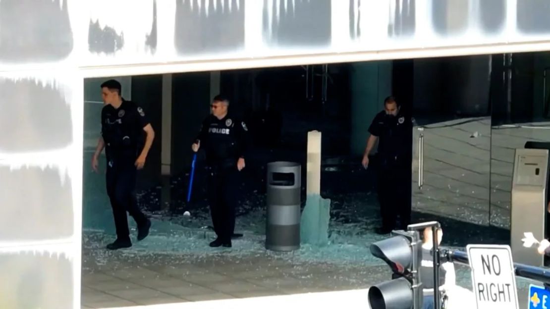 La policía pisa cristales rotos en el Old National Bank de Louisville, Kentucky, este lunes después de un tiroteo masivo. Crédito: WDRB