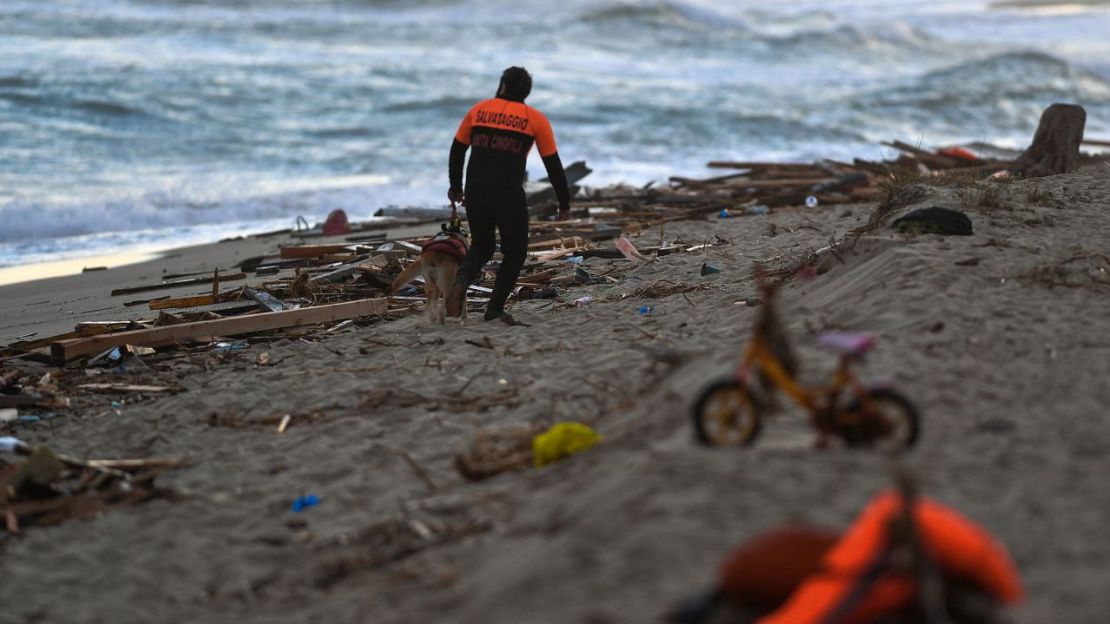 Un policía y su perro patrullan la playa el 26 de febrero de 2023, donde los escombros de un naufragio fueron arrastrados a tierra después de que un barco de migrantes se hundiera frente a la región de Calabria, en el sur de Italia.