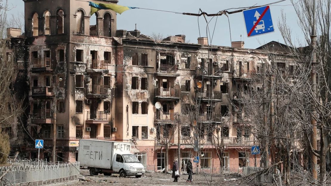 Residentes locales caminan por una calle junto a un edificio dañado durante el conflicto Ucrania-Rusia en la ciudad portuaria sureña de Mariupol, Ucrania, el 3 de abril de 2022.