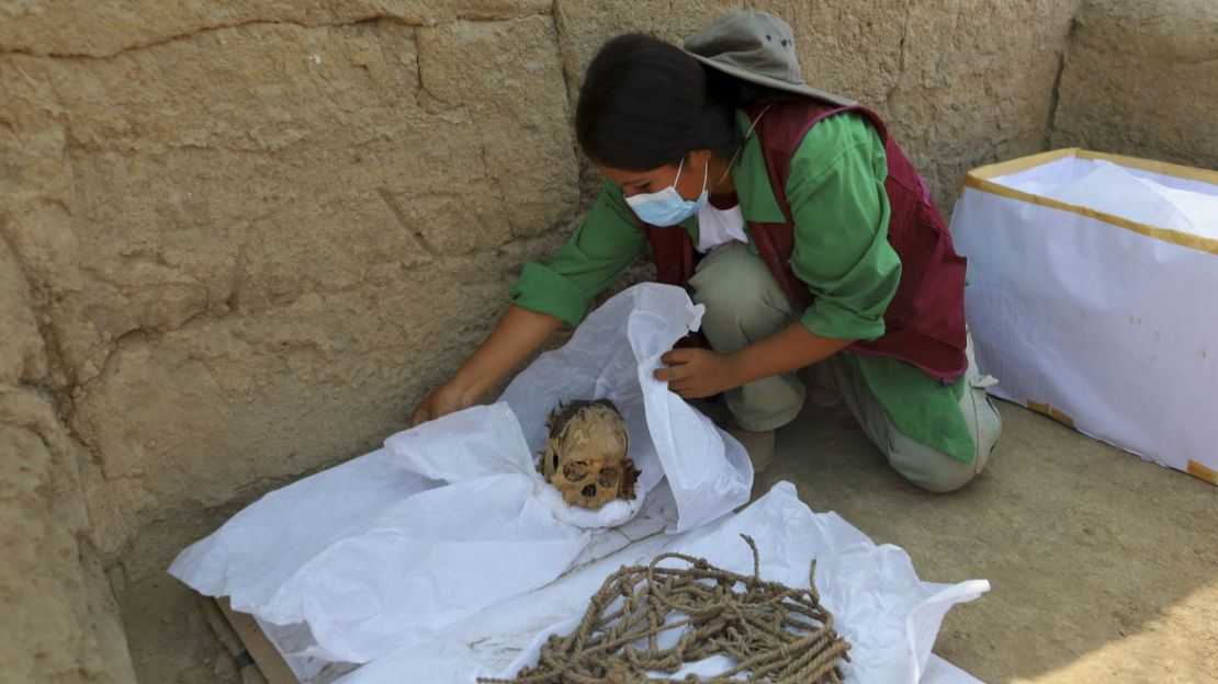 Un trabajador envuelve restos óseos y partes del fardo funerario de la momia. Sebastian Castaneda/Reuters