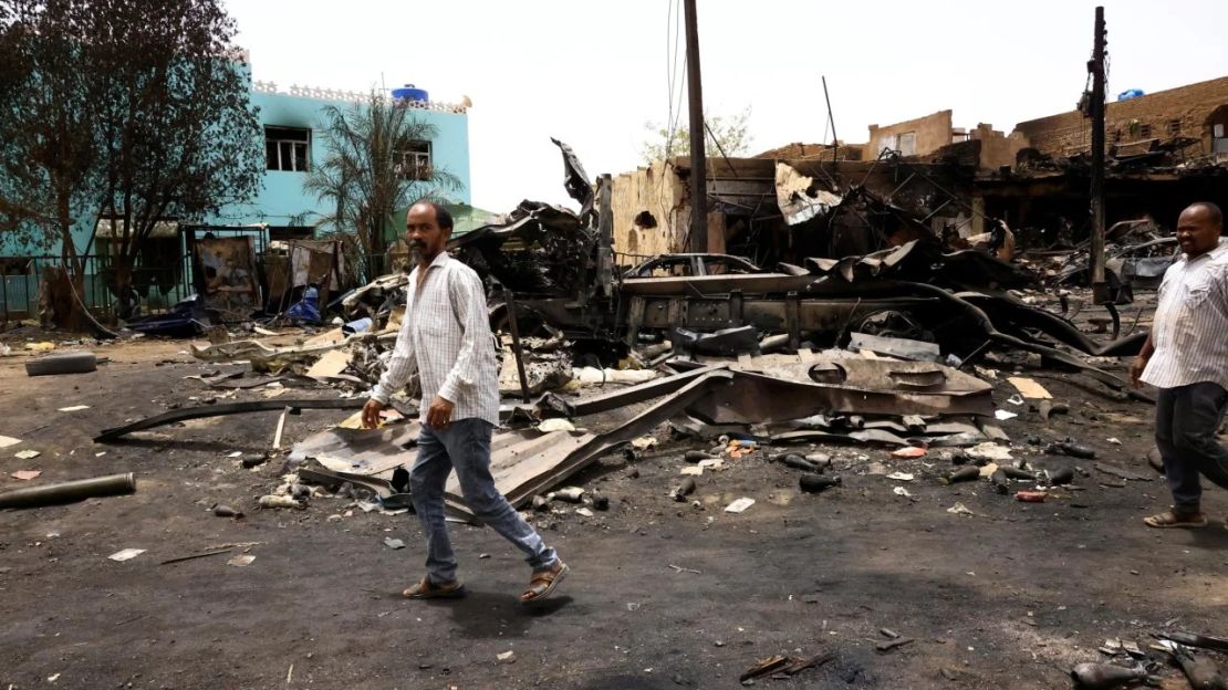 Varios hombres caminan junto a proyectiles en el suelo cerca de edificios dañados en Jartum Norte, Sudán, este jueves, donde la violencia ha dejado a algunos lugareños atrapados en sus casas. Crédito: Mohamed Nureldin Abdallah/Reuters