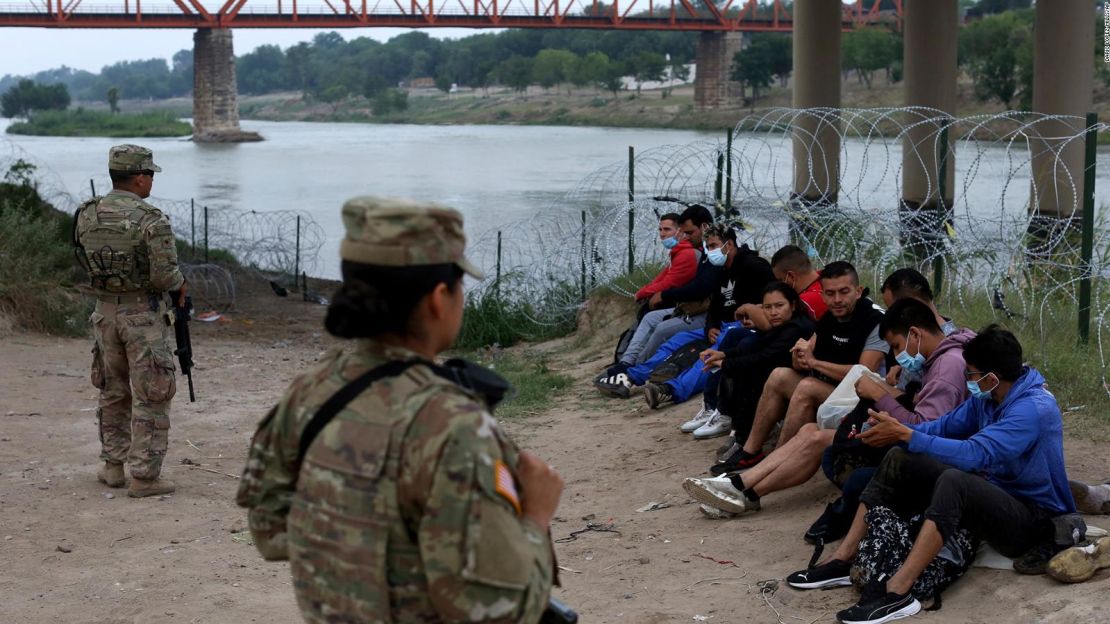 Inmigrantes que cruzaron el río Grande hacia Estados Unidos están bajo custodia de miembros de la Guardia Nacional en Eagle Pass, Texas, el 20 de mayo de 2022.