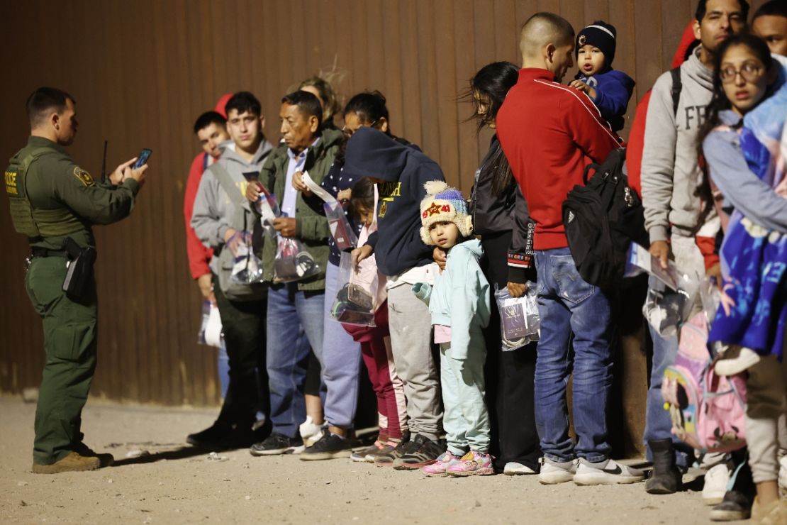 Migrantes que buscan asilo en Estados Unidos hacen fila mientras son procesados ​​por los agentes de la Patrulla Fronteriza en las primeras horas de la mañana después de cruzar a Arizona desde México el 10 de mayo de 2023 en Yuma, Arizona.