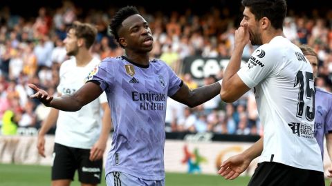 El delantero brasileño del Real Madrid, Vinicius Junior (L), habla con el defensa turco del Valencia, Cenk Ozkacar, mientras reacciona al ser insultado desde las gradas durante el partido de fútbol de la liga española entre el Valencia CF y el Real Madrid CF en el estadio de Mestalla en Valencia el 21 de mayo de 2023.