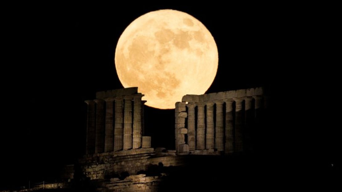 La luna llena de fresa se eleva detrás del Templo de Poseidón en el cabo Sounion, cerca de Atenas, Grecia, en junio de 2022.