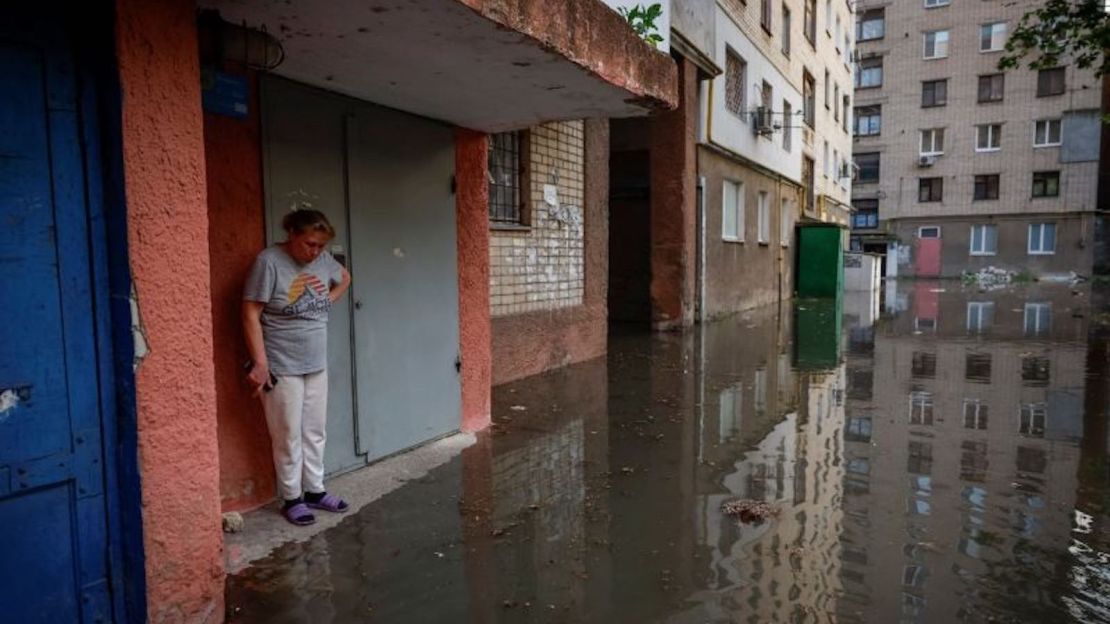 Una mujer se para junto a la entrada de su casa en una calle inundada, tras la rotura de la presa de Nova Kakhovka en Jersón, Ucrania, el 6 de junio.