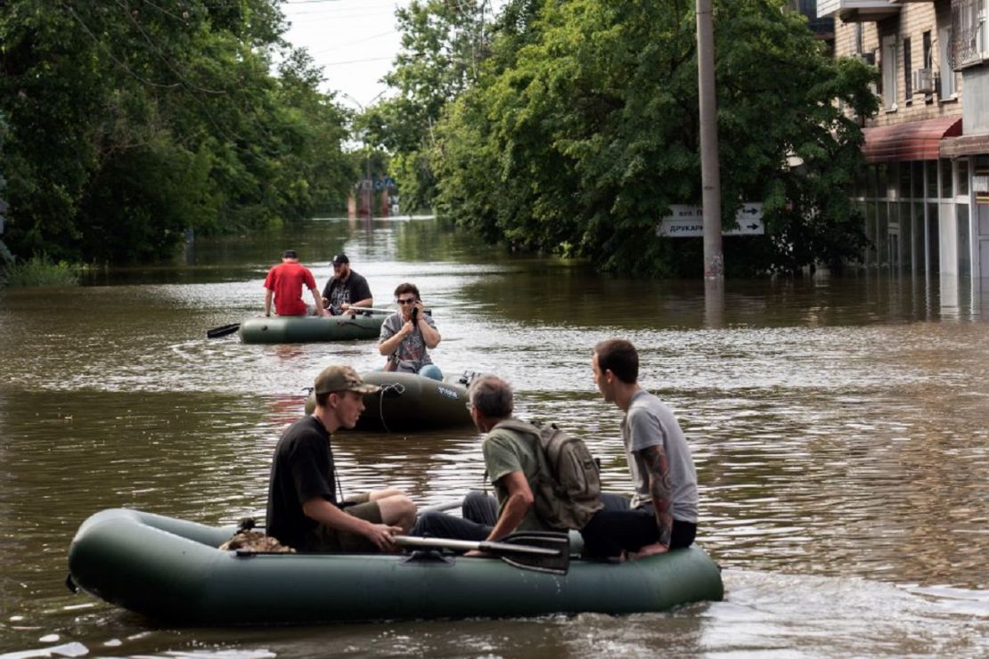 Voluntarios transportan a residentes locales en botes inflables durante una evacuación de una zona inundada en Kherson el 8 de junio de 2023, tras los daños sufridos en la presa de la central hidroeléctrica de Kakhovka.