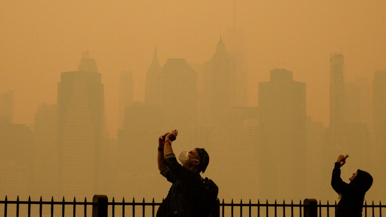 TOPSHOT - People take photos of the sun as smoke from the wildfires in Canada cause hazy conditions in New York City on June 7, 2023. Smoke from Canada's wildfires has engulfed the Northeast and Mid-Atlantic regions of the US, raising concerns over the harms of persistent poor air quality. (Photo by ANGELA WEISS / AFP)