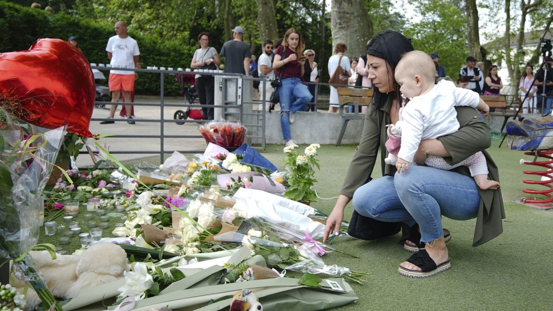 Personas dejan flores cerca de un parque de recreo en Annecy, Francia, donde ocurrió un ataque con cuchillo que dejó a cuatro niños y dos adultos heridos.