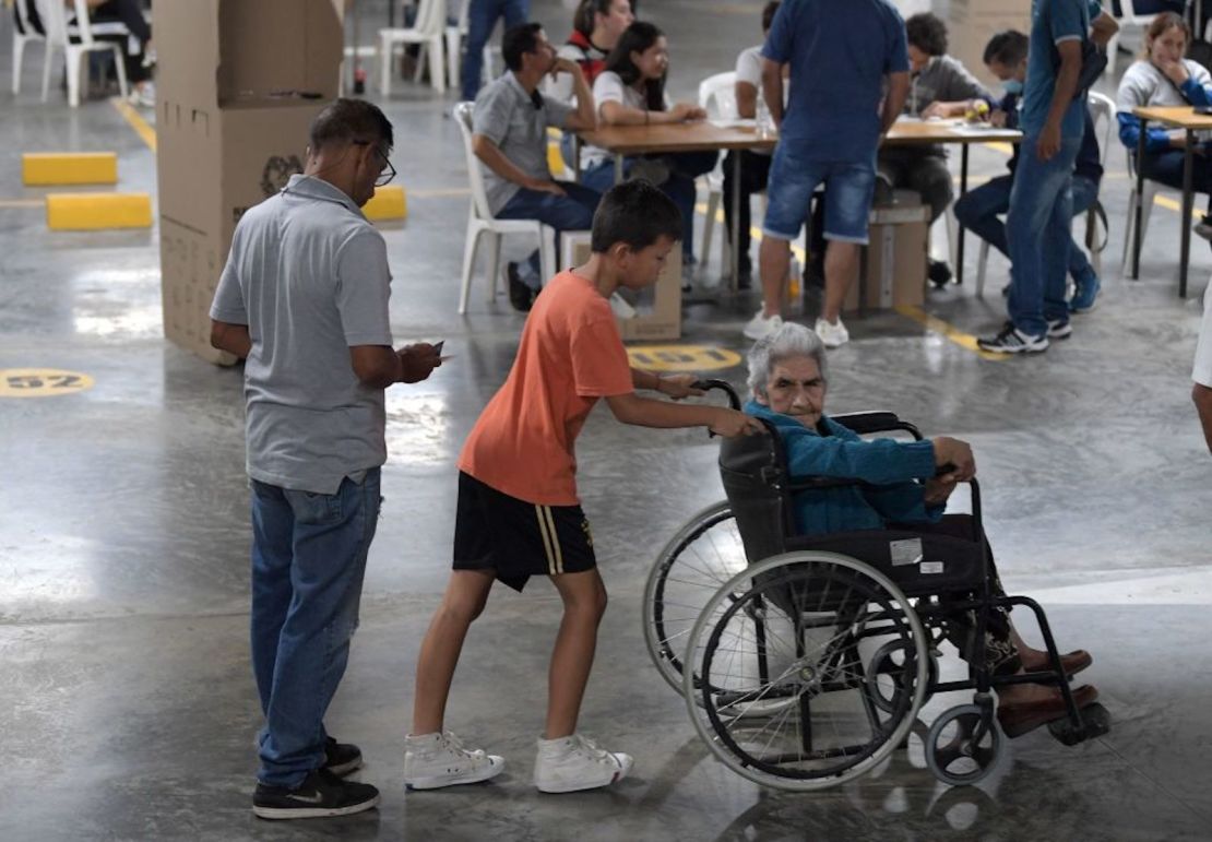 Un niño empuja la silla de ruedas de un anciano en un colegio electoral durante la segunda vuelta de las elecciones presidenciales en Bucaramanga, Colombia, el 19 de junio de 2022.
