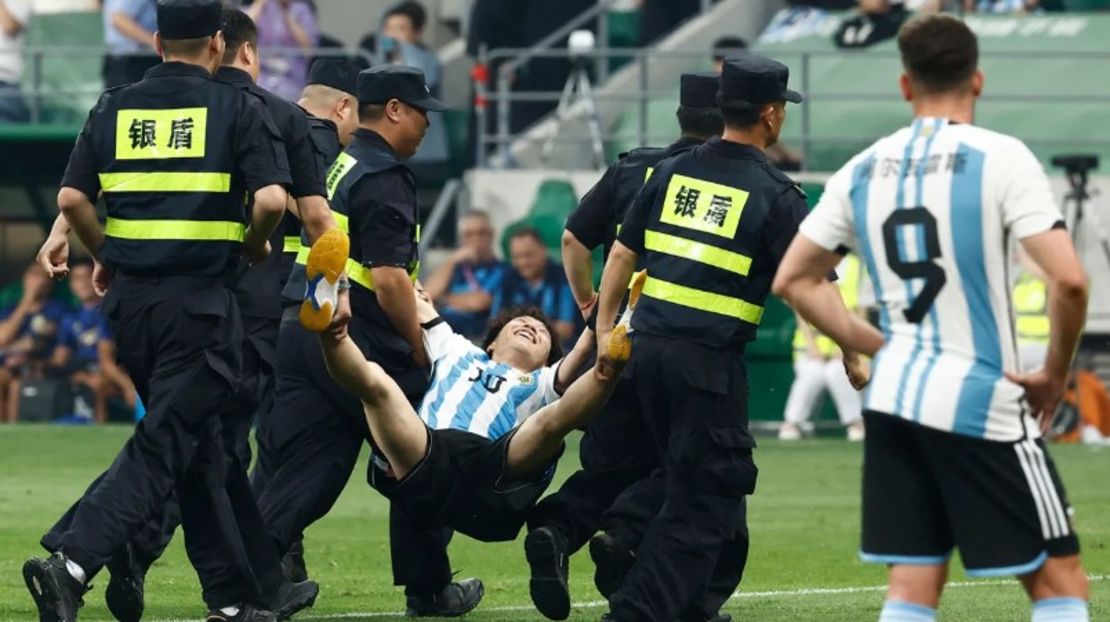 Agentes de seguridad sacan del campo al joven invasor durante un partido en el Estadio de los Trabajadores de Beijing, China, el 15 de junio.