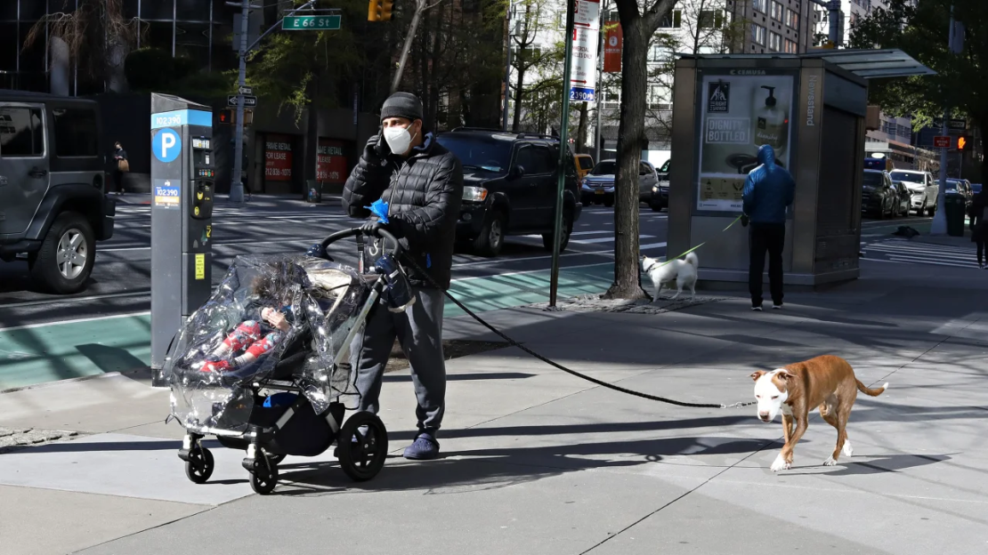 Un hombre habla por teléfono mientras empuja a un niño en un cochecito y pasea a un perro el 20 de abril de 2020 en Nueva York.