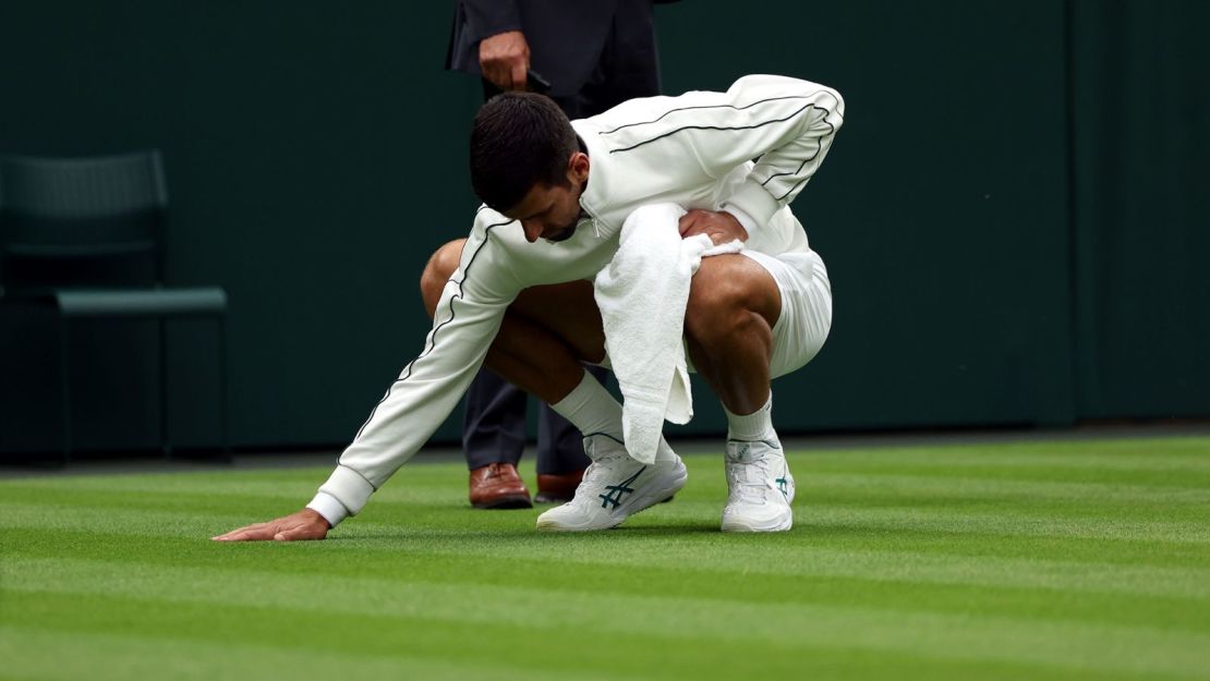 Novak Djokovic toca el césped de la cancha central durante su victoria en la primera ronda contra Pedro Cachín en Wimbledon.