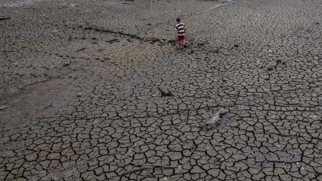 Vista aérea que muestra a un niño caminando en el lecho seco del lago Alhajuela durante la sequía del verano, en la provincia de Colón, a 50 km al norte de la ciudad de Panamá, el 21 de abril de 2023.