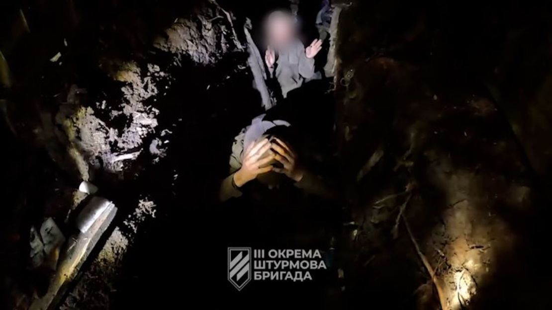 En una captura de pantalla de un video filmado y proporcionado por la Tercera Brigada de Asalto de Ucrania, los soldados ucranianos interrogan a dos rusos sobre su rango, posición y documentos. CNN ha difuminado el rostro de Slava para proteger su identidad.