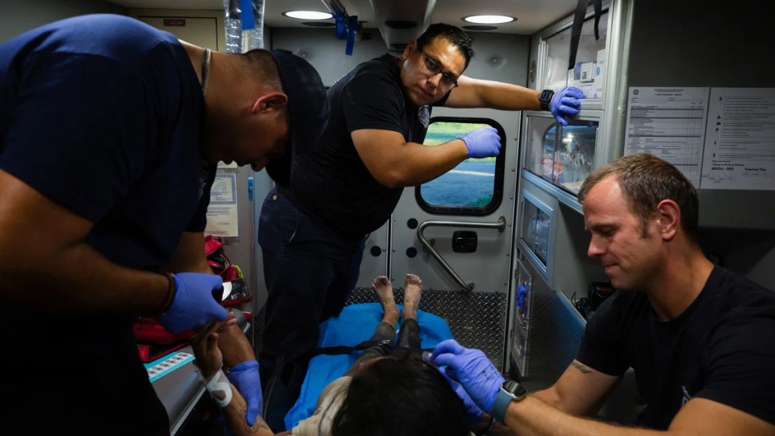 Un equipo de bomberos atiende a una mujer migrante que sufre un golpe de calor en la comunidad fronteriza de Eagle Pass, Texas, EE.UU., el 26 de junio de 2023.