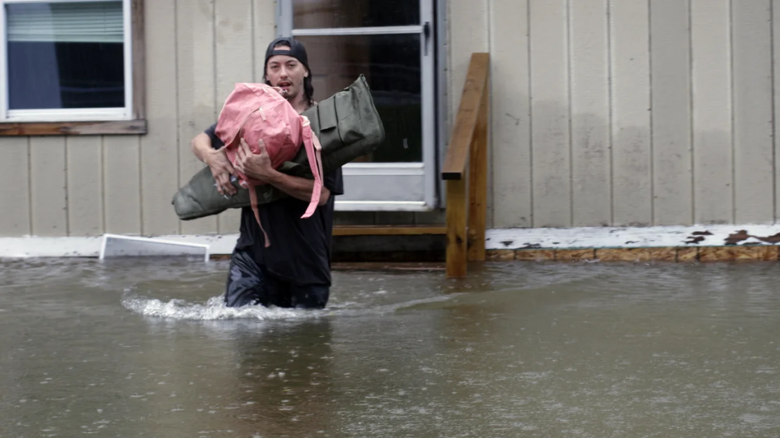 Un hombre transporta sus pertenencias a través de las aguas de una casa en Bridgewater, Vermont, el lunes.