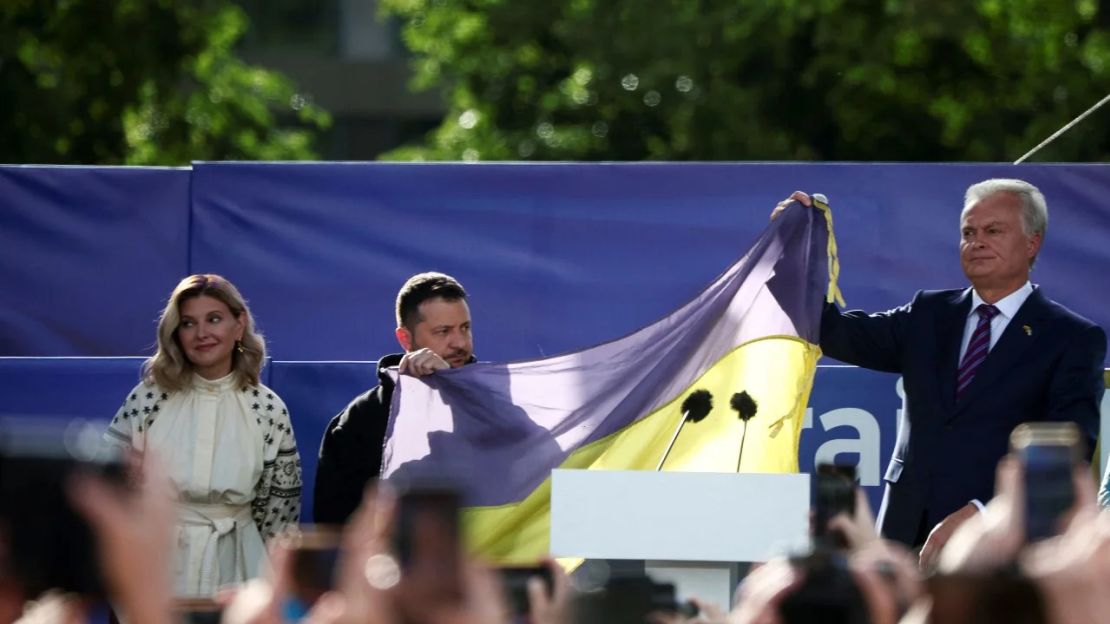 El presidente de Ucrania, Volodymyr Zelensky y el presidente de Lituania, Gitanas Nauseda, sostienen una bandera ucraniana de la primera línea de la guerra con Rusia, junto a Olena Zelenska, en Vilna el 11 de julio de 2023. Crédito: Kacper Pempel/Reuters